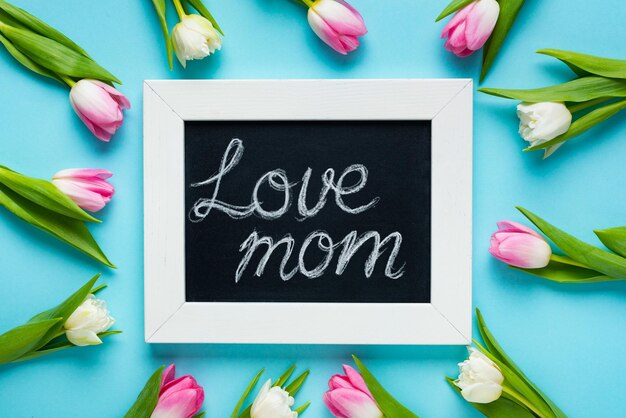 Top view of tulips around chalkboard with love mom lettering on blue background