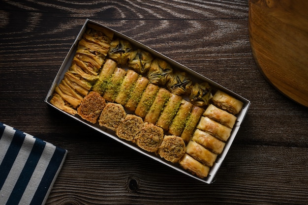 Сладкое тесто турецкой пахлавы с коробкой и деревянной разделочной доской сверху сверху