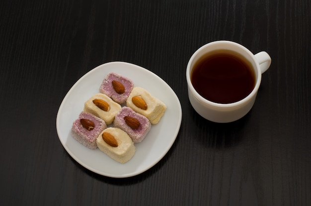 Photo top view of turkish delight with almonds and cup of coffee, black table