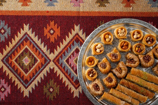 Top view of Turkish desserts on oriental patterned carpet background