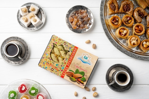 Top view of turkish sweets and turkish coffee on white wooden background