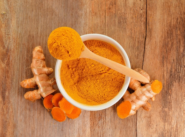 Top view of Turmeric roots with turmeric powder on wooden table