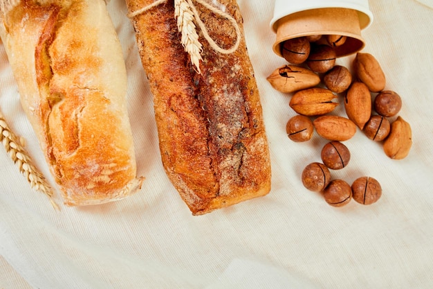 Top view of two baguettebread and nuts on a textile surface