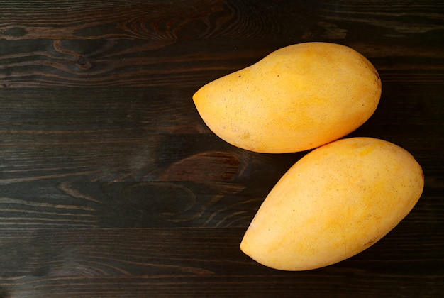 Top View of Two Fresh Ripe Mango Fruits Isolated on Black Wooden Background
