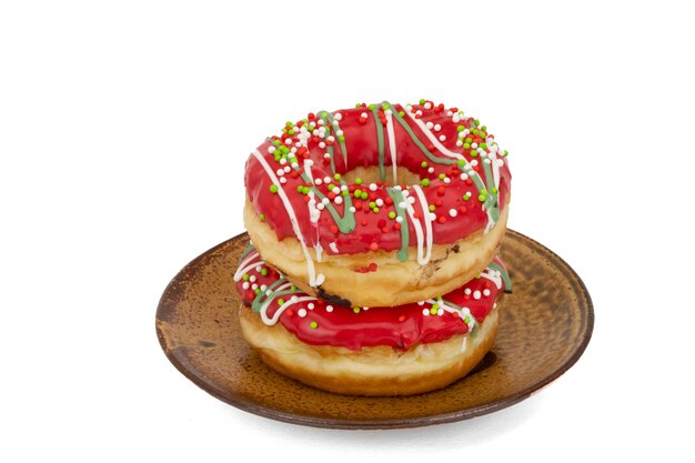 Top view of two frosted, glazed and suagr beads sprinkled donuts on a brown plate.