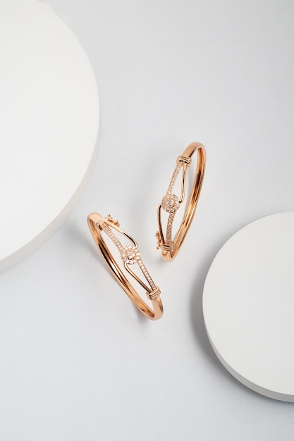 Top view of two golden bracelets on white dramatic background with copy space