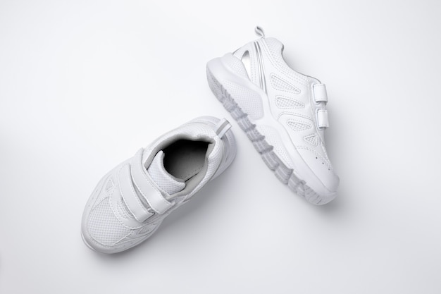 Top view of two white children sneakers with velcro fasteners for easy footwear isolated on a white ...