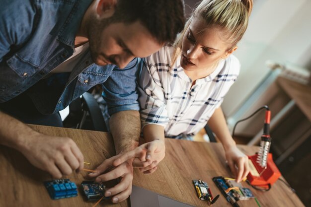 Top view of a two young colleagues technician focused on the repair of electronic equipment.