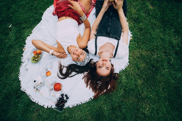 Вид сверху на двух молодых женщин, лежащих в парке