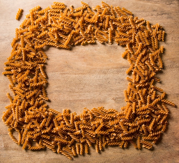 Top view of uncooked pasta integral on a wooden surface