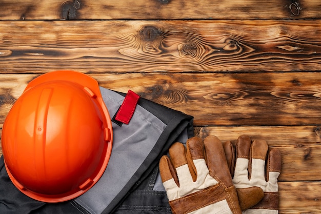 Top view of uniform of construction worker on wooden background