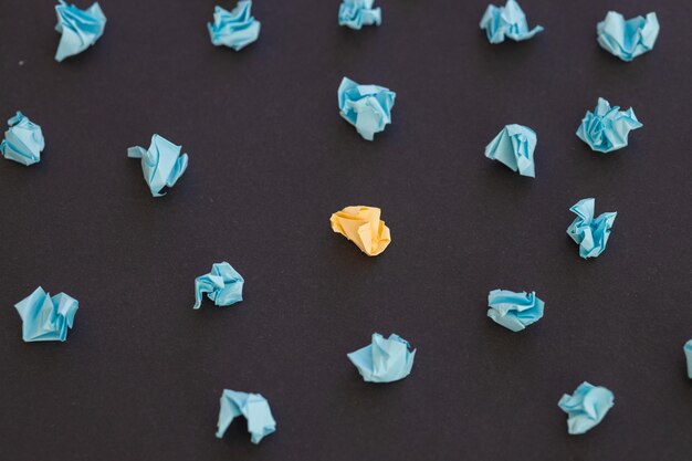 Photo top view of unique crumpled yellow paper among blue on black background new idea in search