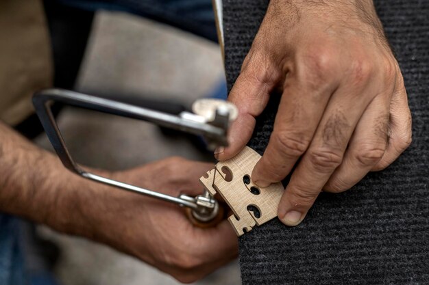 Top view of unrecognizable Latin American luthier using a hacksaw to finish making a violin bridge Concept of stringed instruments