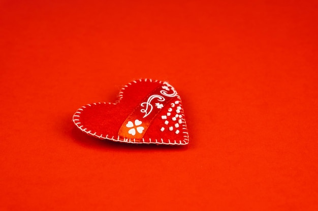 Top view Valentine's Day concept with copy space. Red textile heart on red papper background