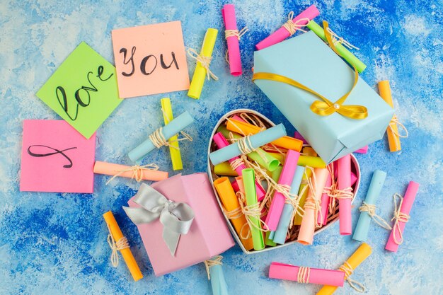 top view valentines day concept i love you written on sticky notes scroll wish papers in heart shaped box gifts on blue background