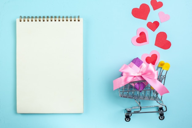 вид сверху день святого валентина концепция красные и розовые сердца ноутбук мини-маркет тележка с подарком на синем фоне