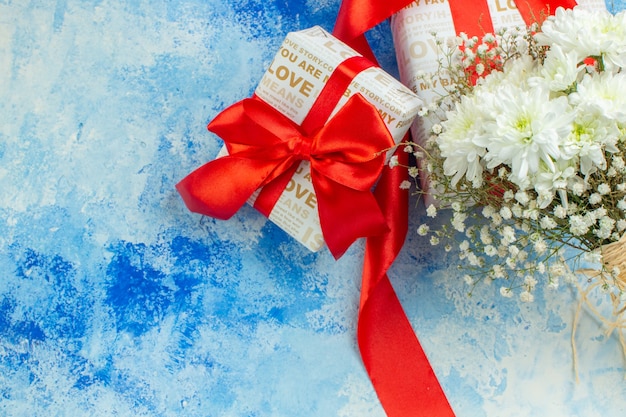 top view valentines day gifts with red ribbons white flowers on blue background copy place