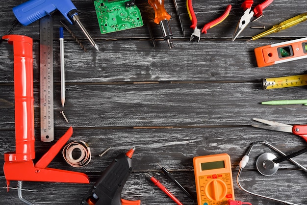 Top view of variety handy tools with different Jobs on black wooden background.