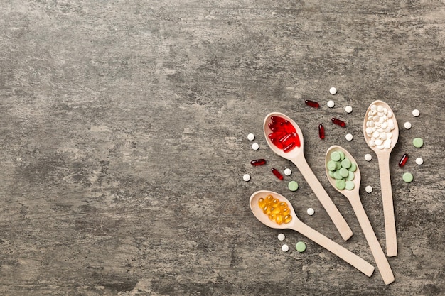 Foto vista dall'alto varietà di pillole di vitamine e minerali in cucchiaio di legno su sfondo colorato vista dall'alto di pillole farmaceutiche assortite prodotto sanitario integratore alimentare