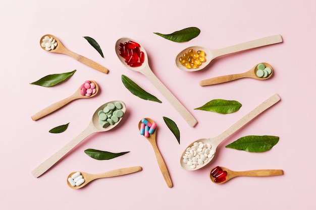 Vista dall'alto varietà di pillole di vitamine e minerali in cucchiaio di legno su sfondo colorato vista dall'alto di pillole farmaceutiche assortite prodotto sanitario integratore alimentare