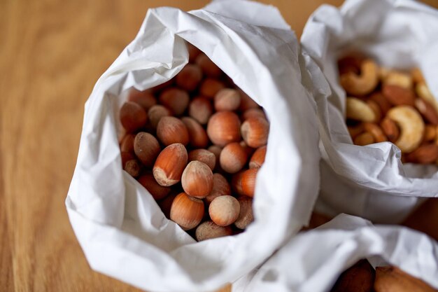 Top view Various sort of nuts on the table in a paper bag on wooden background shopping grocery concept nuts delivary Zero Waste Food Shopping Copy space