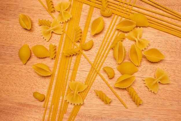 Vista dall'alto vari tipi di pasta italiana su fondo in legno