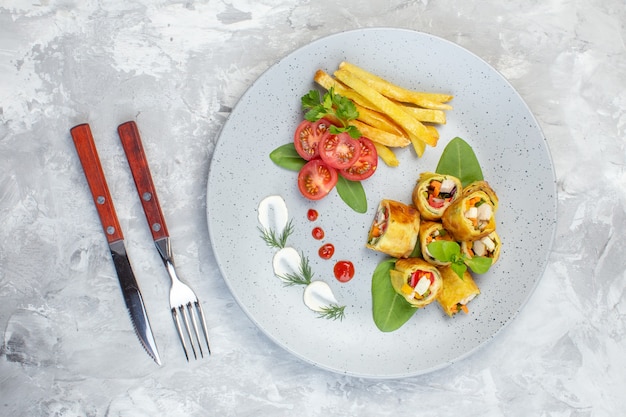 Top view vegetable pate rolls with tomatoes and french fries inside plate on white surface