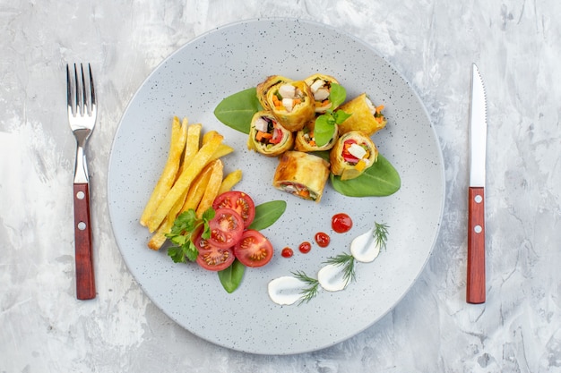 Top view vegetable pate rolls with tomatoes and french fries inside plate on white surface