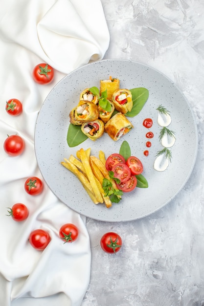 Top view vegetable pate rolls with tomatoes and french fries inside plate on white surface