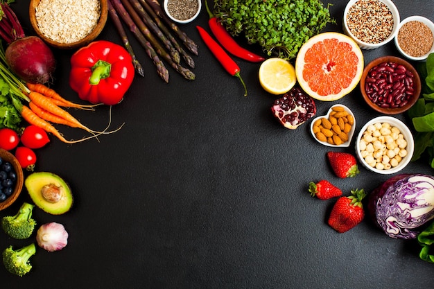 Top view of vegetables, fruits, grains, beans and nuts on a black background. Group of healthy foods for ph eating concept. Copyspace