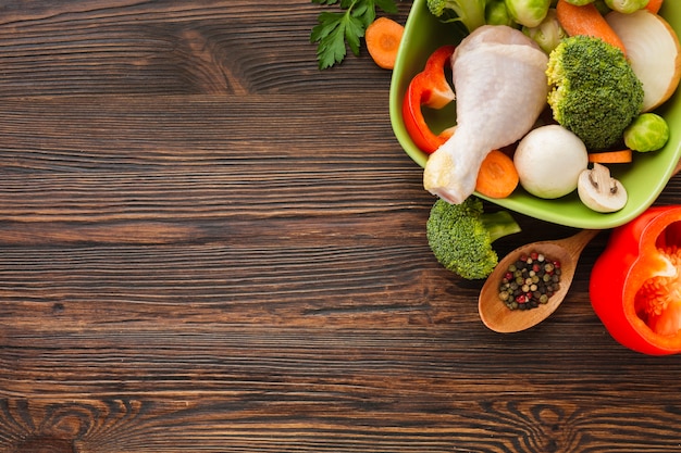 Foto le verdure di vista superiore si mescolano e coscia di pollo in ciotola e cucchiaio di legno con lo spazio della copia