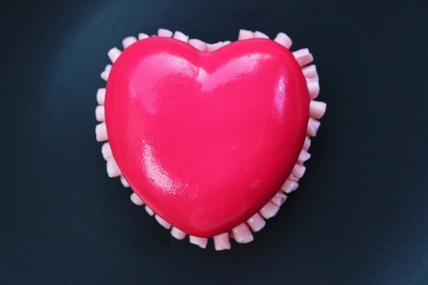 Top View of Vibrant Pink Heart Shaped Strawberry Mousse Cake Isolated on Black Plate