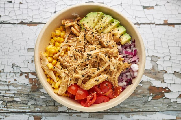 Top-view view of an avocado chicken poke and cherry tomatoes in a bowl