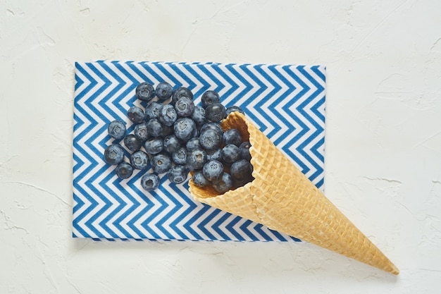 Top view of waffle cone with blueberries on blue textile