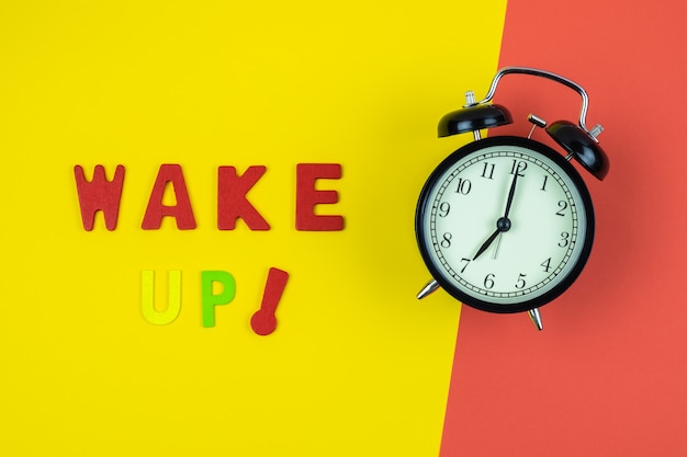 Photo top view of wake up wording with classic clock