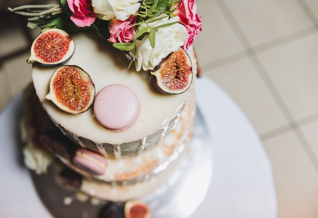 Top view of a wedding cake decorated with fig fruit, macarons and flowers