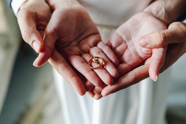 Top view wedding rings in the hands of the newlyweds 