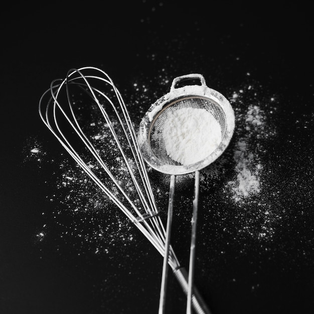 Photo top view whisk with sugar powder on the table