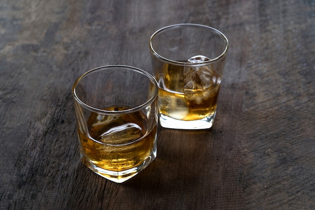 Top view of Whiskey with ice in glass on wooden table 