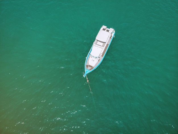 Top view of the white and blue sailing boat cruising the sea in a sunny day, flecks in the turquoise water; regatta concept.