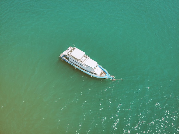 Top view of the white and blue sailing boat cruising the sea in a sunny day, flecks in the turquoise water; regatta concept.