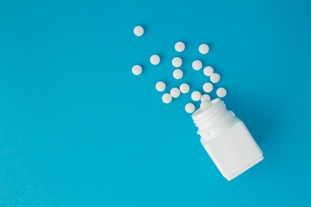 Top view of white bottle and pills on the blue  background