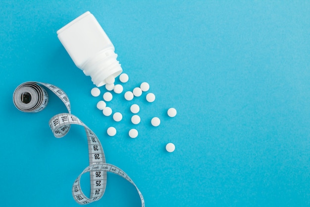 Top view of white bottle, pills and centimeter