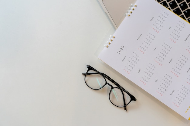 top view on white calendar 2020 schedule with laptop keyboard to make appointment meeting work