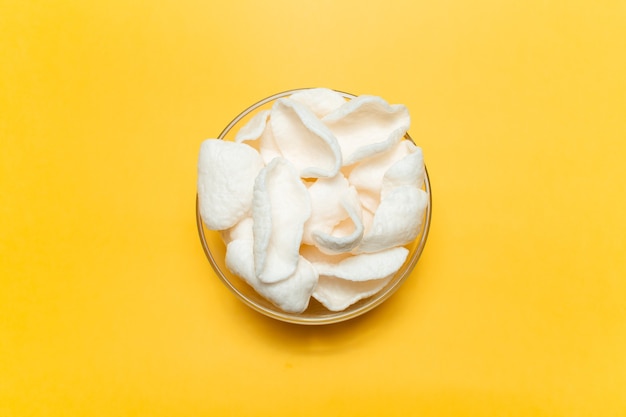 Top view of white chips in bowl on yellow background.