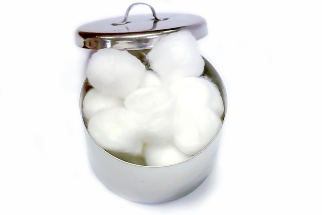 Top view of white cotton in a medical stainless steel cotton container on white background