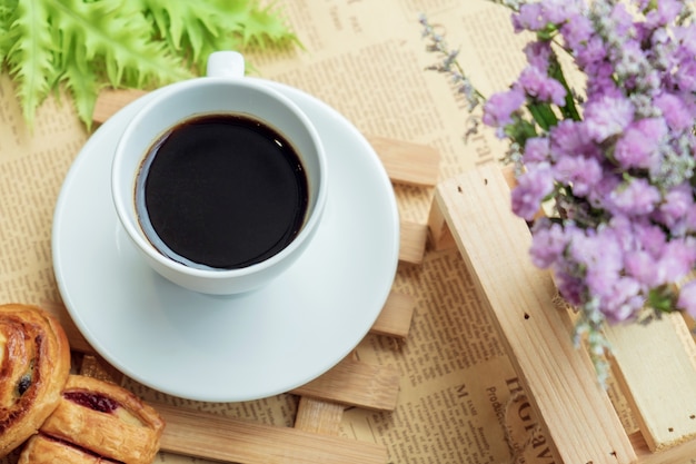 Взгляд сверху белой чашки черного кофе или чая на деревянной плите над запачканным кофейным зерном с