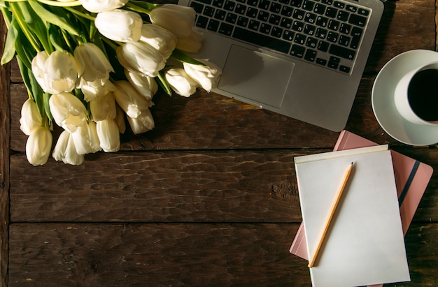 top view of white cup of coffee and laptop on wooden table