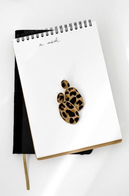 Top view on white desktop with notebooks and earrings