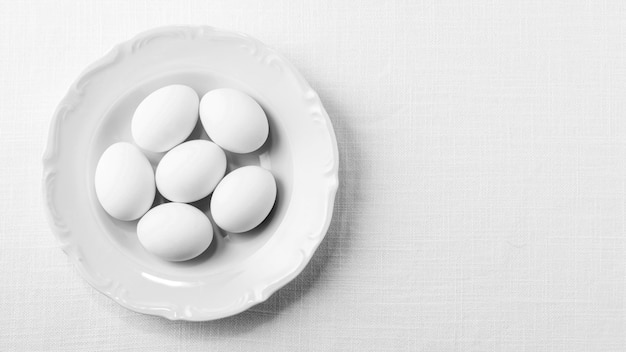 Photo top view white eggs on plate with copy-space
